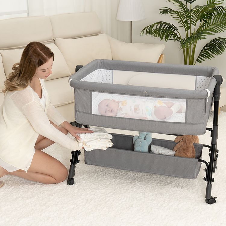 Parent filling the storage basket under a Grey BCOL bassinet